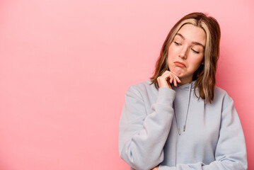 Young caucasian woman isolated on pink background looking sideways with doubtful and skeptical expression.