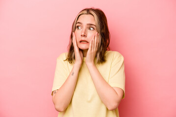 Young caucasian woman isolated on pink background scared and afraid.