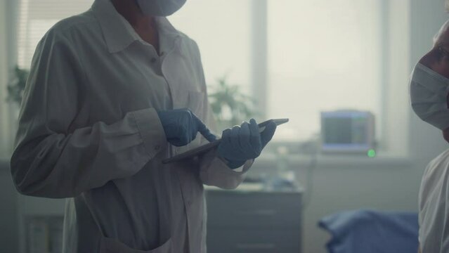 Doctor hands recording results patient checkup on tablet. Doctor consulting man.