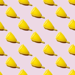 Seamless pattern of yellow menstrual cups isolated on a pink background. Women's health concept. Eco friendly concept. Zero waste concept.