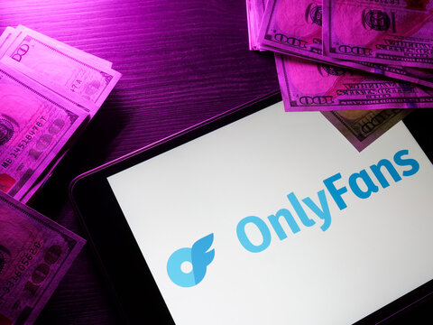 KYIV, UKRAINE - May 4, 2022. Tablet with onlyfans logo and money.