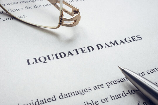 Documents about Liquidated damages with pen and glasses.