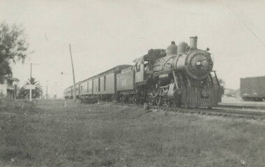 Grayscale of a steamed locomotive in 19th-century railroad