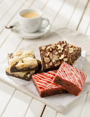 Set of brownies on a wood table, with a coffee cup on the background