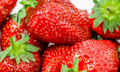 Strawberries in bulk close-up, berries with leaves, selective focus.