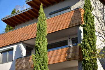 Balkon mit Metall-Geländer, beschichteten Holzplanken und Elektro-Markise an einem Wohnhaus
