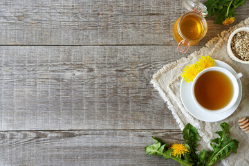 Dandelion tea with fresh dandelion flowers, honey and dried root on a wooden background