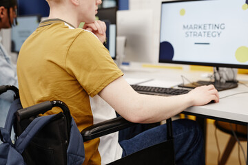 Vibrant closeup of young student with disability doing marketing research in college library