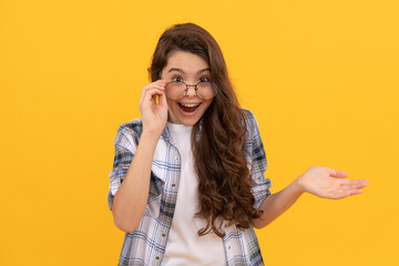 surprised teen kid in checkered shirt and glasses on yellow background