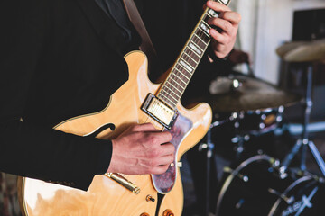 Obraz premium Concert view of an electric guitar player with vocalist and musical jazz band orchestra performing in the background, guitarist on the stage