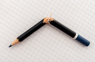Broken pencil on white checkered paper close-up. cracked pencil