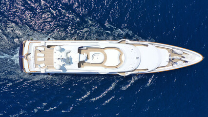 Aerial drone top down photo of luxury yacht with wooden deck cruising in deep blue sea of Mykonos island, Cyclades, Greece