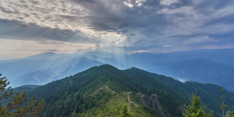 Naklejka premium Crepuscular rays over the mountains before the storm. Colorful sunset over the mountains peak