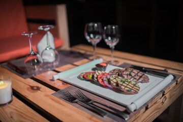 A plate of grilled beef meat with grilled slices of potatoes, tomatoes and onions