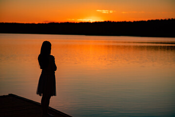 A lady's silhouette against the background of a calm sunset beach