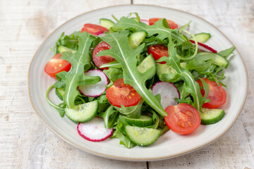 Spring vegan salad with spinach, cherry tomatoes, corn salad, baby spinach, cucumber and radish. Healthy food concept. Wooden table. Top view. 