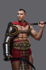 Studio shot of handsome ancient gladiator with naked torso dressed in light armor.