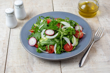 Spring vegan salad with spinach, cherry tomatoes, corn salad, baby spinach, cucumber and radish. Healthy food concept. Gray stone table. Top view. 