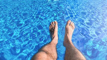 Men's feet splashing in the pool