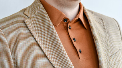 Detail of summer outwear, light beige blazer combined with brown polo. Selective focus.