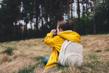 Little explorer, girl with binoculars plays in the forest. Search and research. Travel and adventure concept. Kids club, camping
