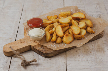 Baked potato wedges with sauces, tomato sauce and mayonnaise served on cutting board - homemade organic vegetable vegan vegetarian potato wedges snack, food meal