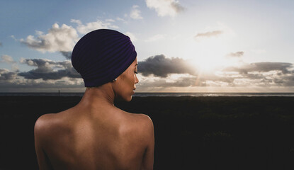 African American woman outside with ocean beach view wearing purple turban