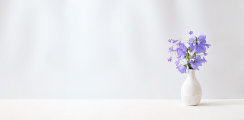 Wildflowers in a vase on a white table. Mock up for displaying works