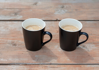 Two black cups of coffee on rustic wood table