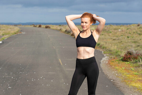 Woman with red hair and freckles working out with exercise outside on beach road