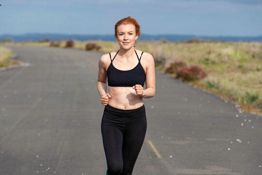 Woman with red hair and freckles working out with exercise outside on beach road