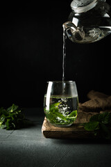 green tea in a glass. Boiling water in the teapot.  Mint tea in the glass on the dark background 