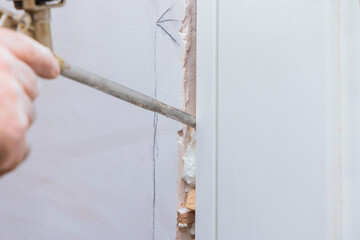Handyman installing door with an mounting foam in a room in using construction foam