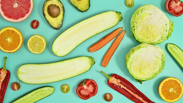 Creative moving pattern with fruits and vegetables on cyan background. Healthy food concept. Stop motion flat lay