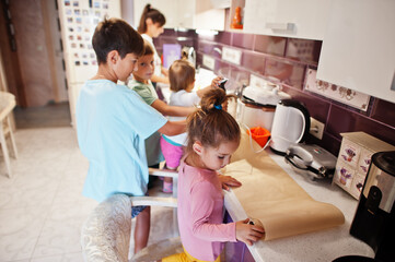 Mother with kids cooking at kitchen, happy children's moments.