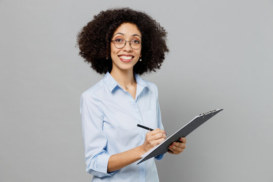 Young smiling fun employee business corporate lawyer woman of African American ethnicity in classic formal shirt work in office clipboard with papers document isolated on grey color background studio.
