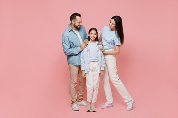 Full body young happy caucasian smiling fun parents mom dad with child kid daughter teen girl in blue clothes look camera hug cuddle isolated on plain pastel light pink background. Family day concept.