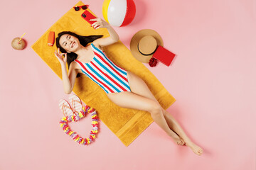 Top view full body young woman of Asian ethnicity in swimsuit lies on towel hotel pool do selfie...