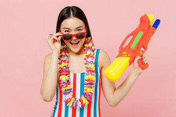 Sexy fun young attractive woman of Asian ethnicity in striped one-piece swimsuit lower glasses hold...