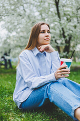 Young beautiful blonde woman in blooming almonds garden.