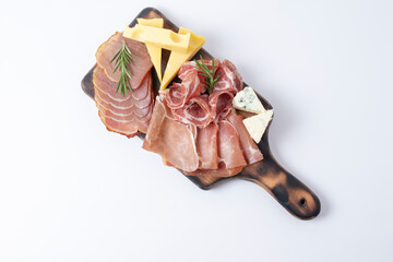 Appetizers table with different antipasti, charcuterie, snacks and cheese. Buffet party. Wooden cutting board isolated on white background, top view