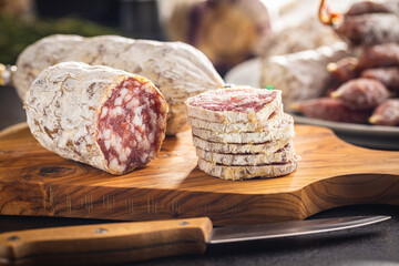 Traditional sausage with white mold. Dried sliced pork salami on cutting board.