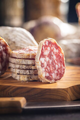 Traditional sausage with white mold. Dried sliced pork salami on cutting board.