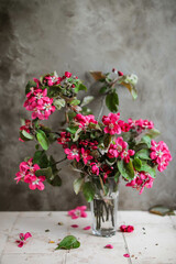 Bright pink apple tree flowers on blooming branches on a beige table. Beautiful spring flowers.