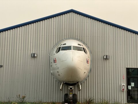 LOS ANGELES, CA, SEP 2021: front view, cockpit of jet aircraft used by FedEx appears to come through hangar wall to street at Museum of Flying, Santa Monica Municipal Airport