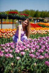Fototapeta na wymiar A young woman in a pink suit stands in a blooming field of tulips. Spring time
