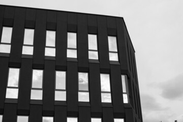 Nowoczesny biurowiec w czerni i bieli. Odbicia w oknach i ciemna elewacja tworzą kontrast