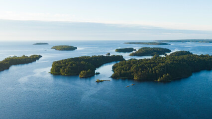 Small rocky islands with a forest in the middle of a large lake in summer at dawn aerial view