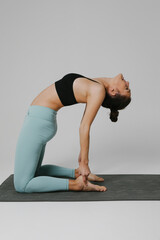 Young woman practicing yoga in the white studio. Mindset concept. Vertical.