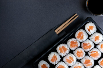 Salmon maki roll on black dark background. Asian traditional salmon sushi maki set, top view with...